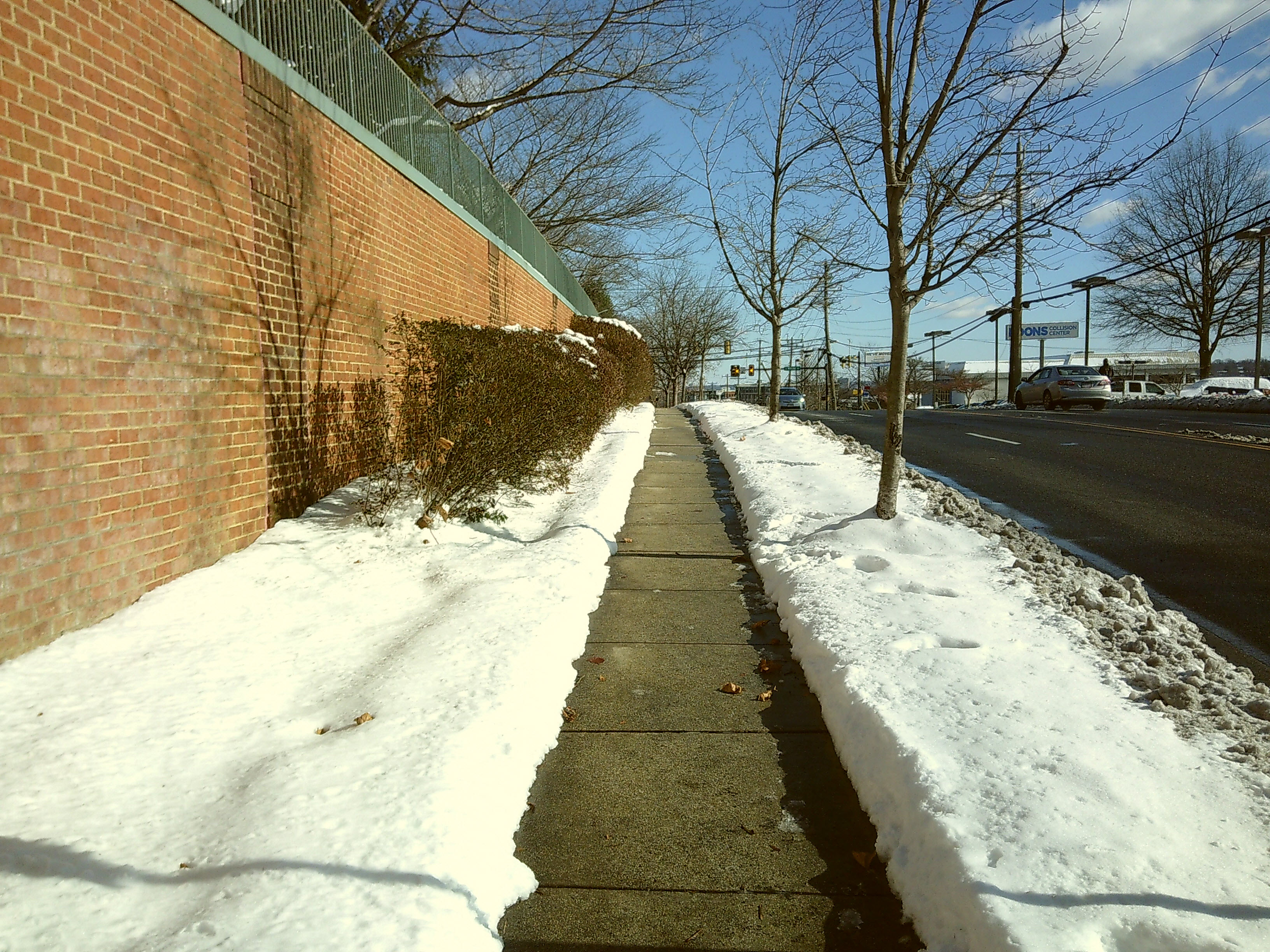 Snow surrounding a clear sidewalk along a suburban street